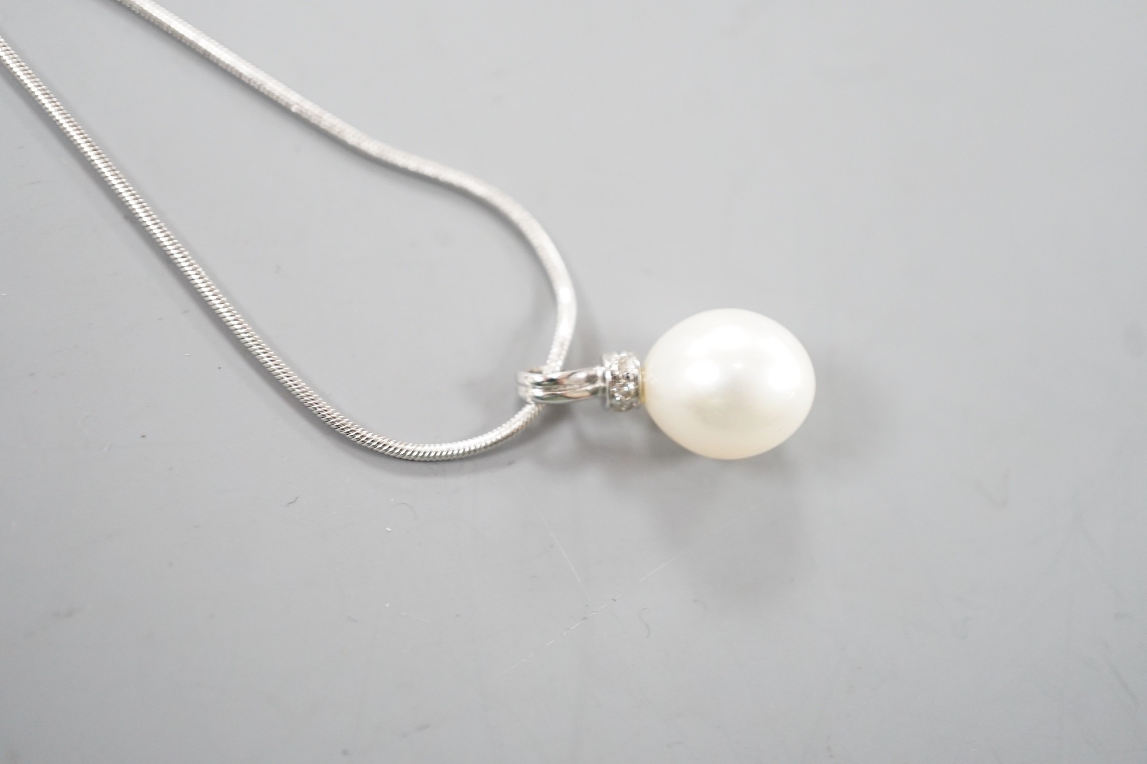 A modern 18ct white, gold, cultured pearl and diamond set pendant, 20mm, gross 2.7 grams, on a modern 9ct white gold chain, 44cm, 4.2 grams.